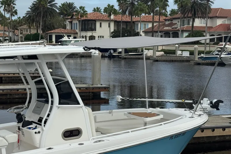 Slide: The Image of Edgewater 230CC 2019 boat docked in a marina with waterfront homes in the background. - 28