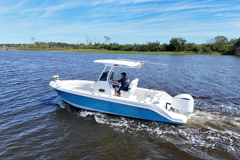 Slide: The Image of 2019 Edgewater 230CC boat cruising on a scenic lake under a clear blue sky. - 3
