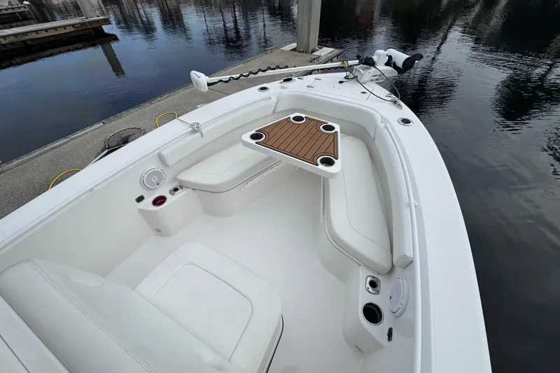 Slide: The Image of 2019 Edgewater 230CC boat interior with seating and table, docked by calm water. - 30