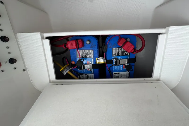 Slide: The Image of Battery compartment of a 2019 Edgewater 230CC boat, featuring dual blue batteries. - 39
