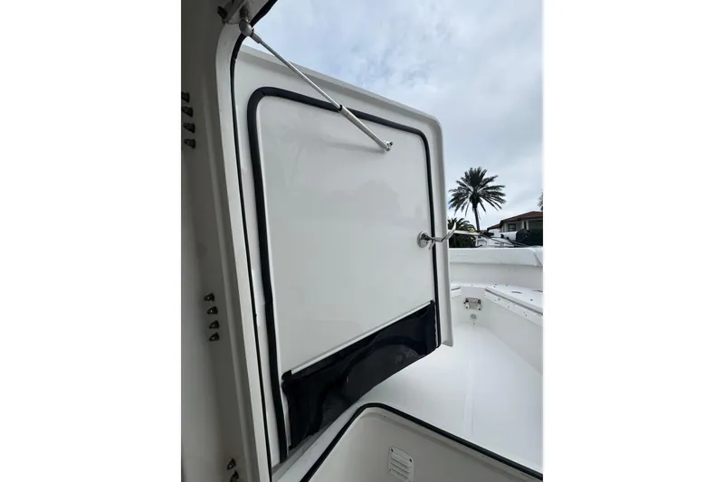 Slide: The Image of 2019 Edgewater 230CC boat interior with open storage compartment and visible palm tree. - 41