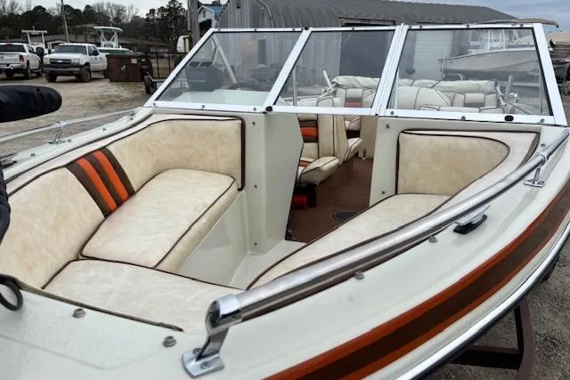 Slide: The Image of 1986 Galaxie Bowrider boat with beige seating and orange accents, parked outdoors. - 12