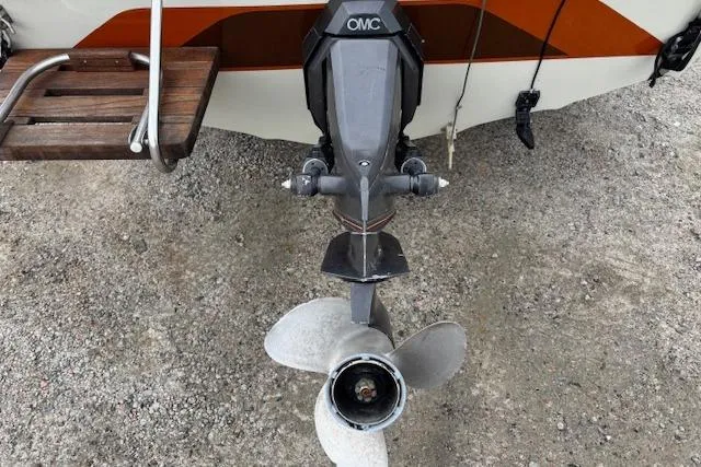 Slide: The Image of 1986 Galaxie Bowrider boat with OMC outboard motor and propeller on gravel surface. - 24