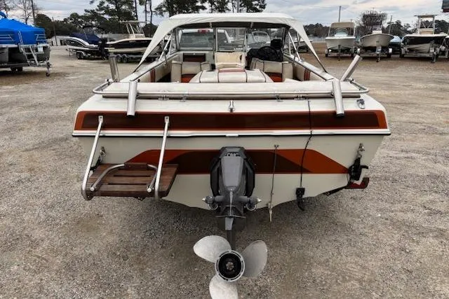 Slide: The Image of 1986 Galaxie Bowrider boat, rear view, parked on gravel lot with other boats. - 4
