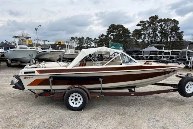 Slide: The Image of 1986 Galaxie Bowrider boat on trailer, parked in a marina with other boats. - 6