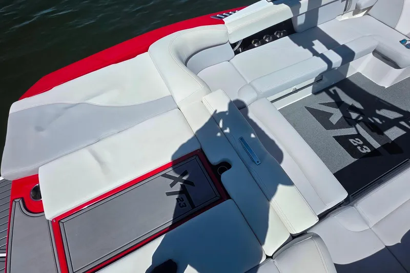 Slide: The Image of 2018 MasterCraft XT23 boat interior with white seating and red accents. - 10