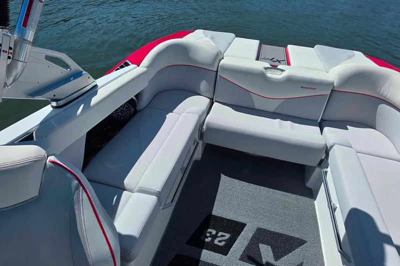 Slide: The Image of 2018 MasterCraft XT23 boat interior with white seating and red accents on the water. - 13