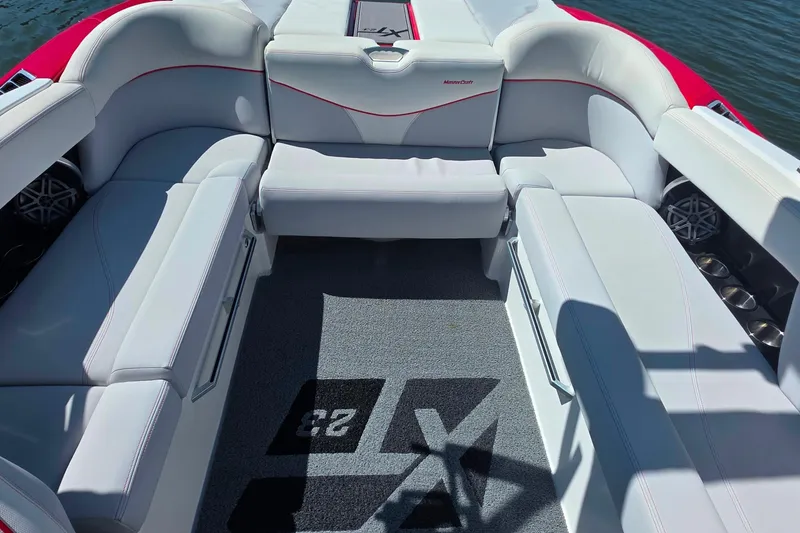 Slide: The Image of 2018 MasterCraft XT23 boat interior with white seating and logo carpet. - 15