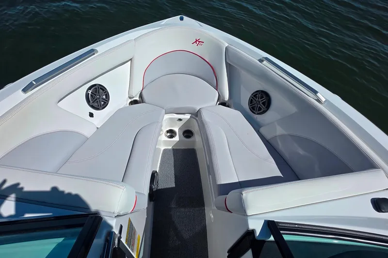 Slide: The Image of 2018 MasterCraft XT23 boat interior with white seating and speakers on a sunny day. - 17