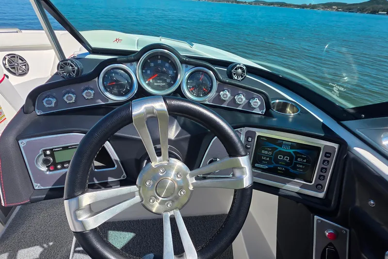 Slide: The Image of 2018 MasterCraft XT23 boat dashboard with steering wheel and digital display on a sunny day. - 19