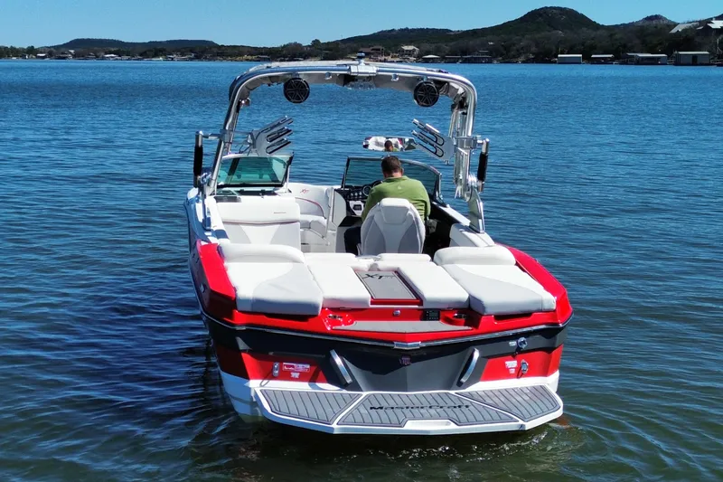 Slide: The Image of 2018 MasterCraft XT23 boat on a lake, featuring red and white design. - 2