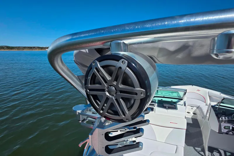 Slide: The Image of 2018 MasterCraft XT23 boat with speaker, sleek interior, and lake view. - 26