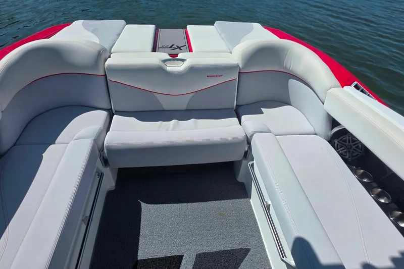 Slide: The Image of 2018 MasterCraft XT23 boat interior with white seating and red accents on the water. - 30