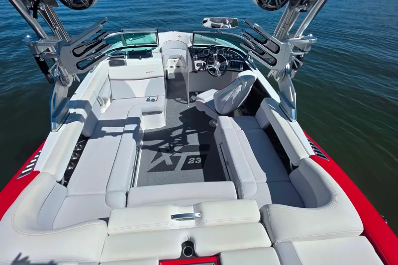 Slide: The Image of 2018 MasterCraft XT23 boat interior with white seating and advanced dashboard on water. - 33