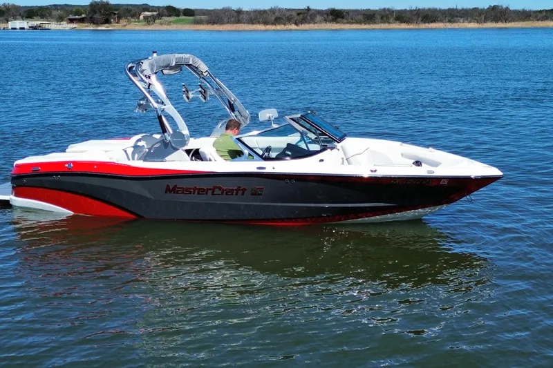 Slide: The Image of 2018 MasterCraft XT23 boat on a calm lake, featuring sleek design and vibrant colors. - 5