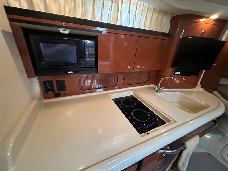 Slide: The Image of 2003 Sea Ray 340 Sundancer galley with microwave, stove, sink, and TV. - 44