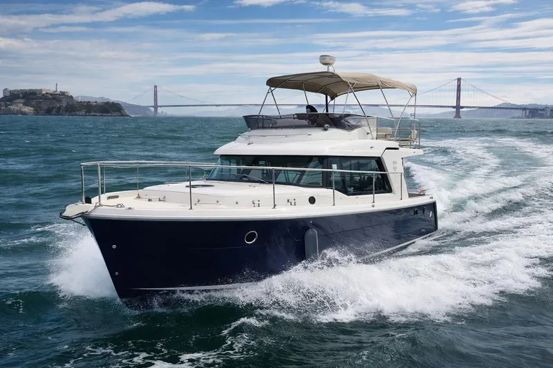 The Image of 2016 Beneteau Swift Trawler 30 cruising near iconic bridge on a sunny day. - 0