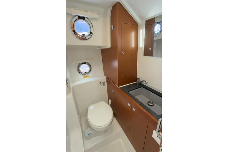 Slide: The Image of Bathroom interior of 2016 Beneteau Swift Trawler 30 with sink, toilet, and porthole windows. - 11