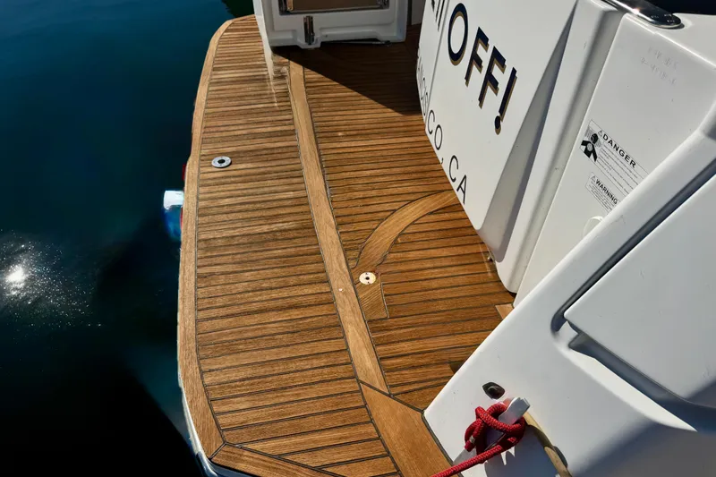 Slide: The Image of 2016 Beneteau Swift Trawler 30 teak deck with water reflection and safety warning. - 37