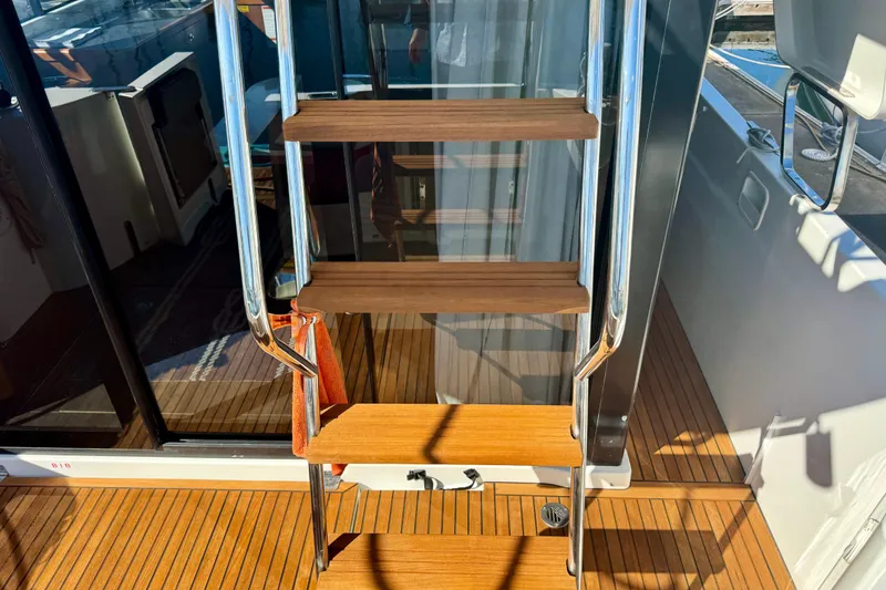 Slide: The Image of Stairs on 2016 Beneteau Swift Trawler 30 with wooden steps and metal railings. - 38