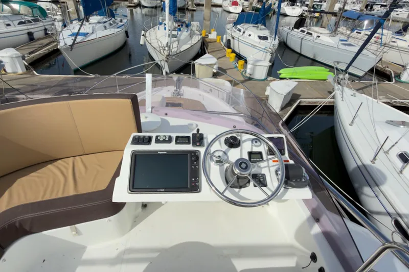 Slide: The Image of Helm of 2016 Beneteau Swift Trawler 30 at marina, featuring navigation controls and seating. - 42
