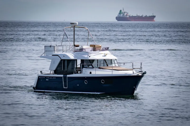 Slide: The Image of 2016 Beneteau Swift Trawler 30 cruising on open sea with distant cargo ship. - 5