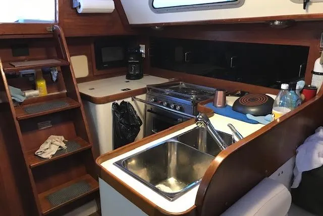 Slide: The Image of Interior of 1989 Freedom 38 Sloop sailboat kitchen with sink, stove, and wooden cabinetry. - 10