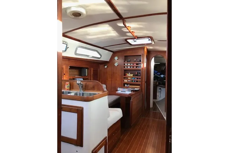 Slide: The Image of Interior of 1989 Freedom 38 Sloop, featuring wood finishes and compact kitchen area. - 11