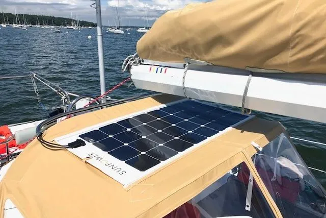 Slide: The Image of 1989 Freedom 38 Sloop with solar panel on deck, anchored in a scenic bay. - 22