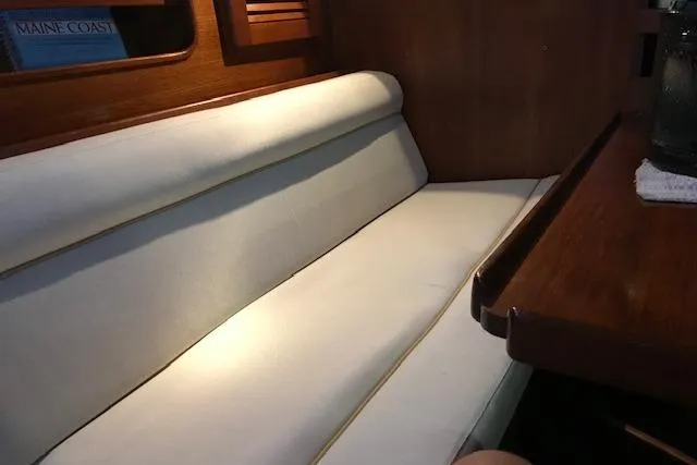 Slide: The Image of Interior of 1989 Freedom 38 Sloop, featuring a cozy white cushioned seating area. - 3