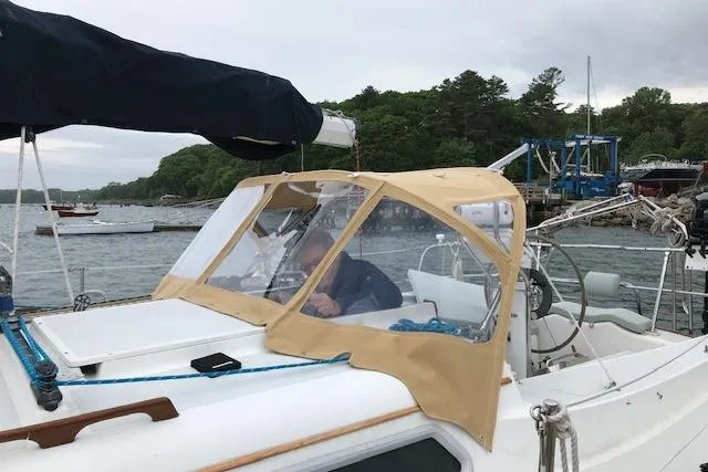 Slide: The Image of 1989 Freedom 38 Sloop sailboat docked, featuring tan canopy and scenic waterfront backdrop. - 34
