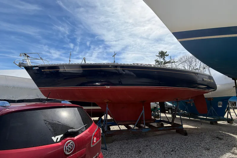Slide: The Image of 1989 Freedom 38 Sloop sailboat on dry dock, with red hull and blue upper deck. - 40