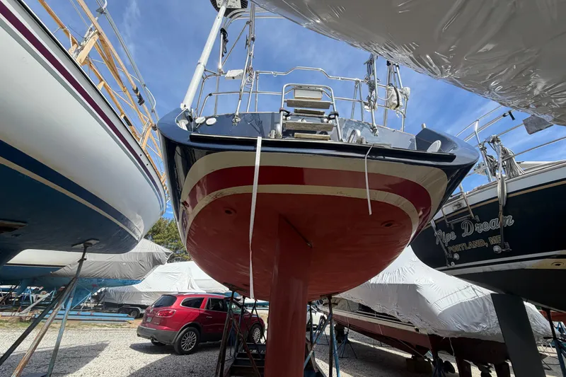 Slide: The Image of 1989 Freedom 38 Sloop sailboat on dry dock, surrounded by other boats and a red SUV. - 42
