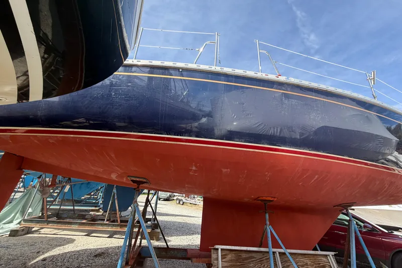 Slide: The Image of 1989 Freedom 38 Sloop sailboat on stands, showcasing red hull and blue upper section. - 43