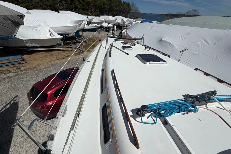 Slide: The Image of 1989 Freedom 38 Sloop sailboat in storage, surrounded by covered boats and parked cars. - 48