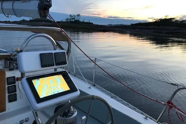 Slide: The Image of 1989 Freedom 38 Sloop sailboat at sunset, featuring navigation equipment and serene waters. - 69