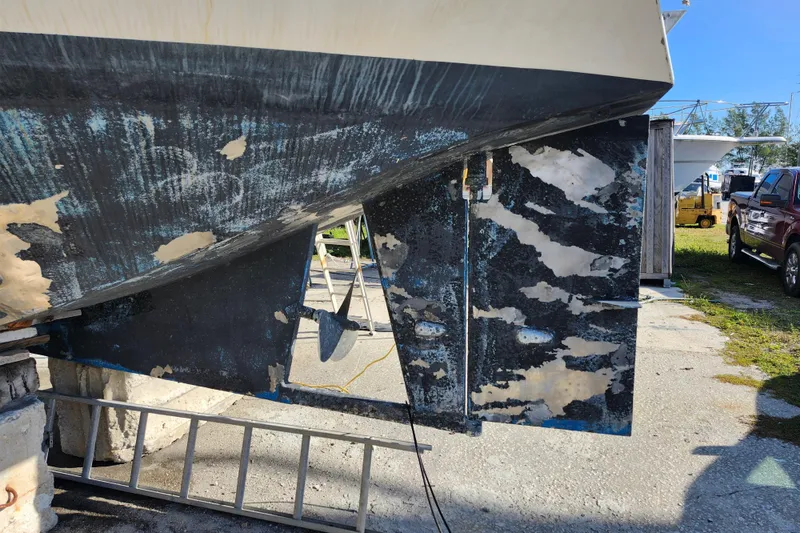 Slide: The Image of 1987 Custom Weld Exploration boat hull with visible wear and peeling paint, docked outdoors. - 10