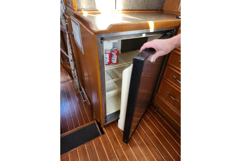 Slide: The Image of 1987 Custom Weld Exploration boat interior with open fridge and wooden cabinetry. - 16