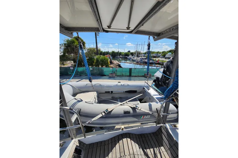 Slide: The Image of 1987 Custom Weld Exploration boat with inflatable dinghy, docked at a marina under clear skies. - 56