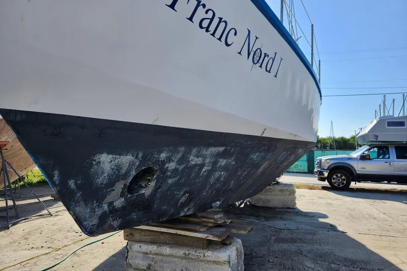 Slide: The Image of 1987 Custom Weld Exploration boat on blocks, showing hull and nearby truck. - 8