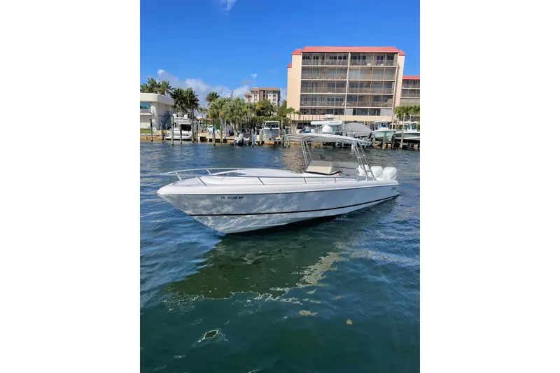 The Image of 2010 Intrepid 323 Cuddy boat on water near marina and buildings. - 0