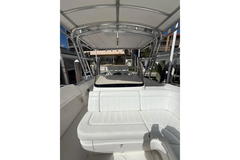 Slide: The Image of 2010 Intrepid 323 Cuddy boat with white seating and canopy, docked in marina. - 14