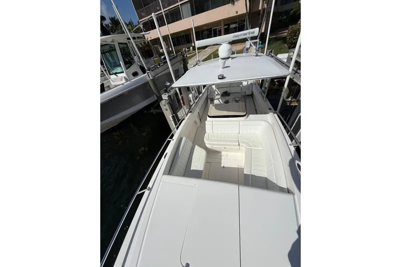 Slide: The Image of 2010 Intrepid 323 Cuddy boat docked, featuring spacious seating and sleek design. - 18