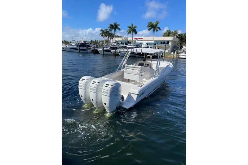 Slide: The Image of 2010 Intrepid 323 Cuddy boat with triple 300 horsepower engines docked in marina. - 2