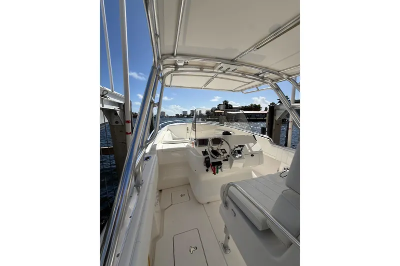 Slide: The Image of 2010 Intrepid 323 Cuddy boat interior with helm, docked by the water. - 9