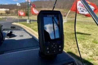 Slide: The Image of 2025 Tracker Bass Tracker Classic XL with Garmin device, flags in background. - 11