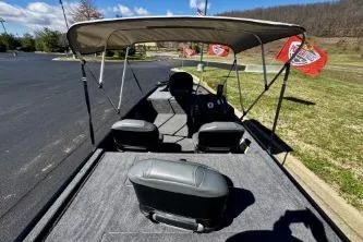 Slide: The Image of 2025 Tracker Bass Tracker Classic XL boat with canopy, parked on pavement near grassy area. - 7
