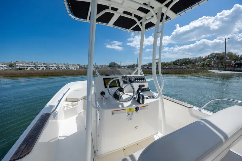 Slide: The Image of 2022 Boston Whaler 190 Montauk boat on water, clear sky, residential background. - 13