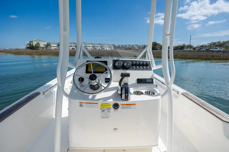 Slide: The Image of 2022 Boston Whaler 190 Montauk boat console with steering wheel and controls on calm water. - 17
