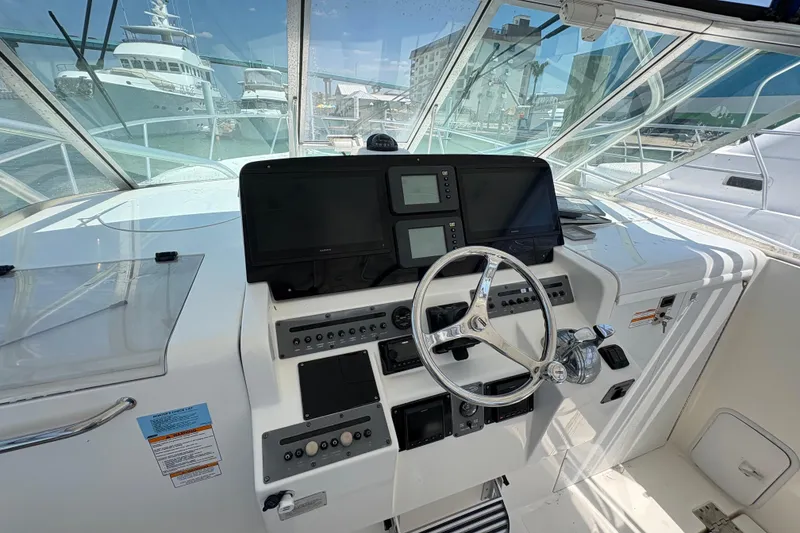 Slide: The Image of 2006 Rampage 38 Express helm with steering wheel and navigation displays in marina setting. - 23